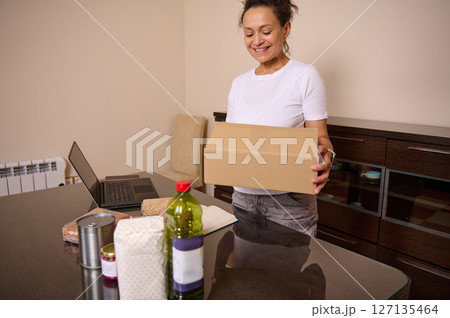 Woman Smiling While Inspecting a Package in a Cozy Home Setting Woman Smiling While Inspecting a Package in a Cozy Home Setting 127135464