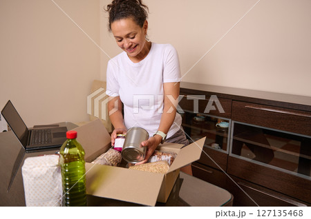 Woman Packing Essentials from Home Desk with Care and Diligence 127135468