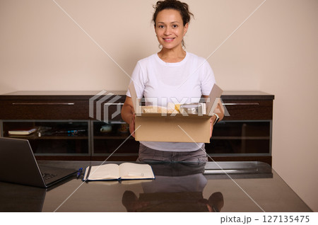 Smiling Woman With a Gift Box in a Home Office Environment Smiling Woman With a Gift Box in a Home Office Environment 127135475