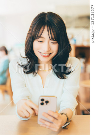 カフェでスマートフォンを使う笑顔の女性 127135577