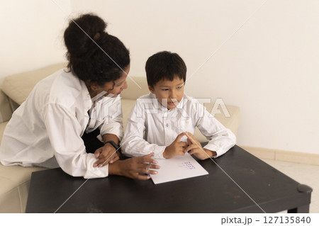 Teacher helping young boy with homework at home Teacher helping young boy with homework at home 127135840
