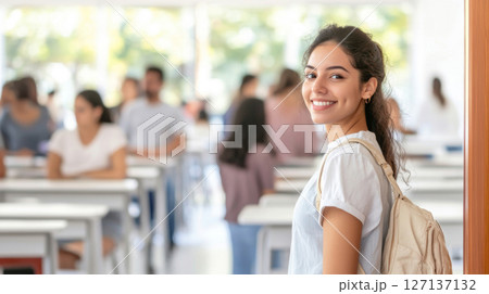 Young latin american woman entering classroom door smiling, educational environment 127137132
