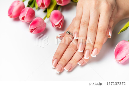 Woman showing french manicure and pink tulips on white background Woman showing french manicure and pink tulips on white background 127137272