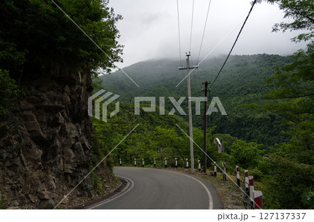 Turn of the road with incredible view of mountains and forest in fog, cloudy Turn of the road with incredible view of mountains and forest in fog, cloudy 127137337