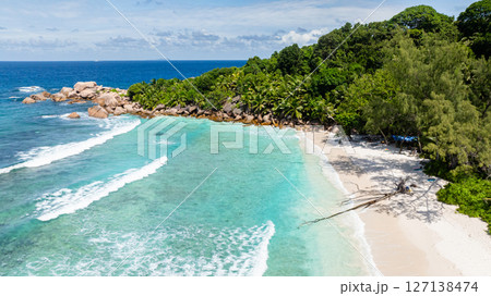 Clear turquoise waters gently meeting the sandy shore, creating a serene scene. La Digue, Seychelles. Clear turquoise waters gently meeting the sandy shore, creating a serene scene. La Digue, Seychelles. 127138474