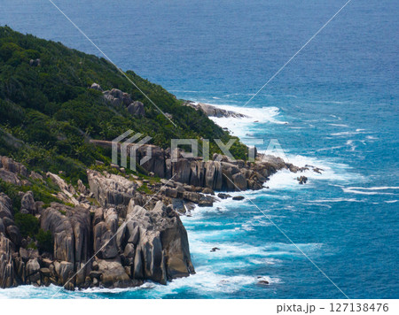 Granite cliffs border the ocean with turquoise waves splashing. Seychelles, Felicite. 127138476