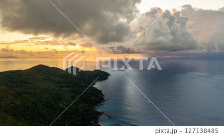 Sunset casts warm hues over a calm bay bordered by silhouetted hills, creating a serene atmosphere. Seychelles, Mahe. Sunset casts warm hues over a calm bay bordered by silhouetted hills, creating a serene atmosphere. Seychelles, Mahe. 127138485