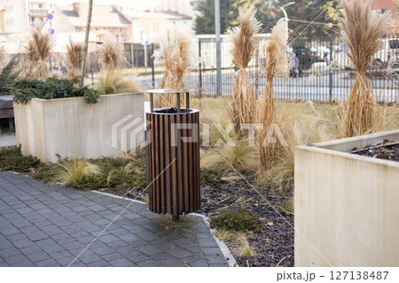 Wooden Public trash can on a city street filled with garbage. Garbage bin in park with blurred background Wooden Public trash can on a city street filled with garbage. Garbage bin in park with blurred background 127138487
