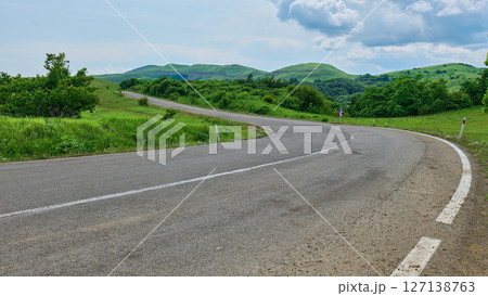 Scenic road winding through green fields and hills. High quality photo 127138763