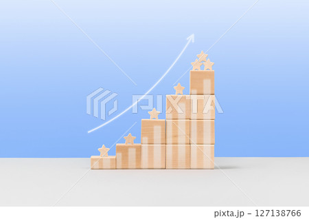 Wooden blocks in form of graphical steps up and white arrow of business growth process, start-up, business goals management, sustainable financial plan. Action plan, profit, economic improvement 127138766
