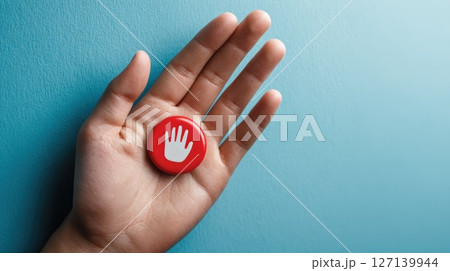 Hand Holding a Red Button Featuring a White Hand Symbol on Blue Background 127139944