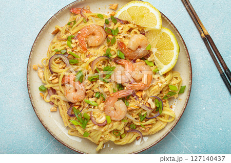 Pad thai noodles with shrimps and chopsticks on light blue background, traditional dish of Thailand Pad thai noodles with shrimps and chopsticks on light blue background, traditional dish of Thailand 127140437