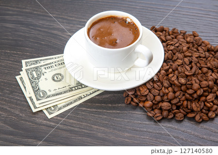 Enjoying a cup of coffee with fresh beans and a touch of cash on a wooden table. coffee business 127140580