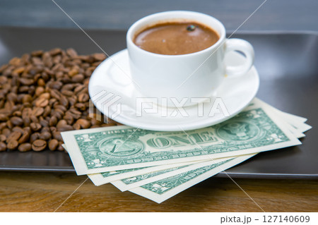 Coffee, money, and business. A cup of espresso with roasted coffee beans and U.S. currency 127140609