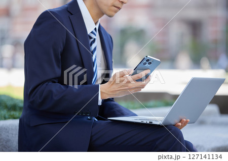 ビジネス街でスマホで通話するスーツの若い男性 127141134