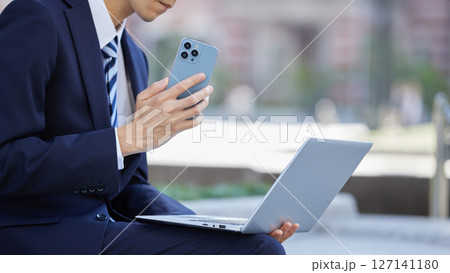 ビジネス街でスマホで通話するスーツの若い男性 ビジネス街でスマホで通話するスーツの若い男性 127141180