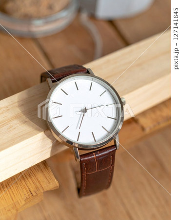 Silver Minimalist Wristwatch with Brown Leather Strap on Light Wood 127141845