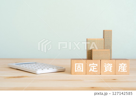 固定資産と書かれたブロック、不動産の模型、電卓 127142585