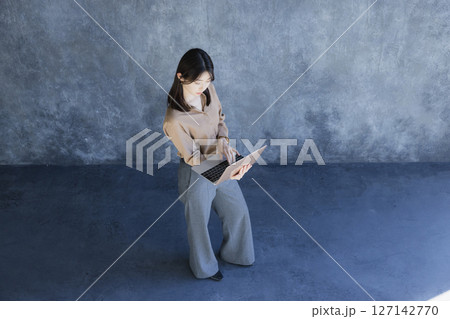 ノートパソコンを持って立っている女性 127142770