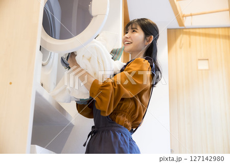 ドラム式洗濯機から洗濯物を取り出す女性 ドラム式洗濯機から洗濯物を取り出す女性 127142980