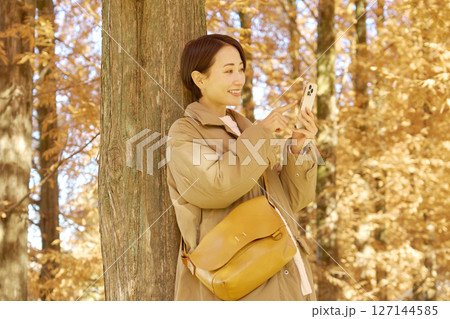 紅葉の中でスマホを使う女性　ミドルエイジ 127144585