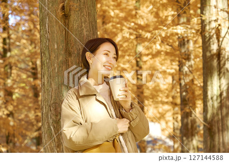 紅葉の中をコーヒーを飲む女性　ミドルエイジ 127144588