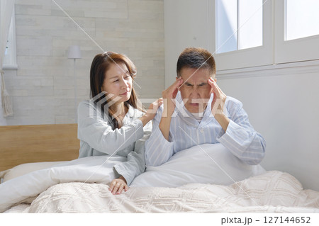ベットの上で頭痛がする男性 127144652