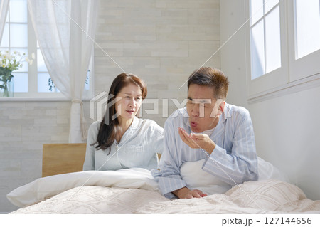 ベットの上で吐き気がする男性 127144656