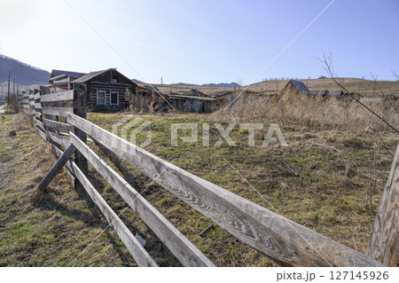 A street with an abandoned dilapidated house with antique window frames in Gorny Altai A street with an abandoned dilapidated house with antique window frames in Gorny Altai 127145926