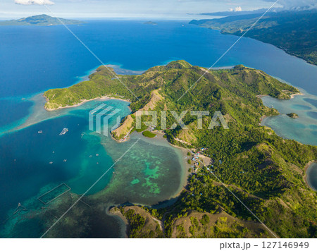 Tropical island surrounded azure water atoll and coral reefs. Sleeping Dinosaur Island. Mati, Davao Oriental. Philippines. 127146949