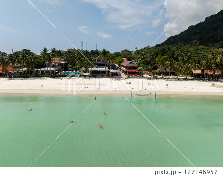Resorts lined along the sandy beach with turquoise waters and lush tropical backdrop. Ko Pha Ngan, Thailand. 127146957