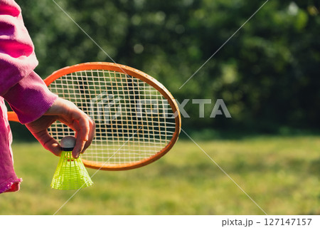Woman hand holding wooden Badminton racket and shuttlecock. Outside recreation and fresh air. Healthy lifestyle nature connection sport summer activities. Stress relief hobby 127147157