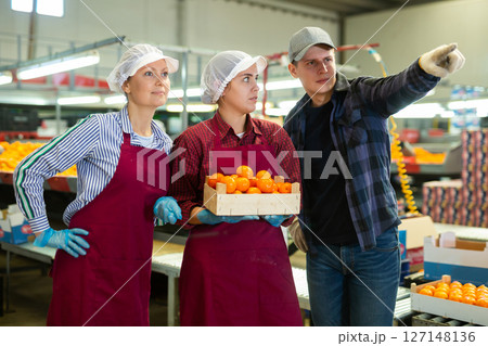 Young foreman of fruit factory giving instructions to female workers Young foreman of fruit factory giving instructions to female workers 127148136