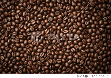 Macro shot displaying of uniform layer of dark roasted coffee beans, organic pattern showcases the rich texture and varying tones of each bean. 127148402