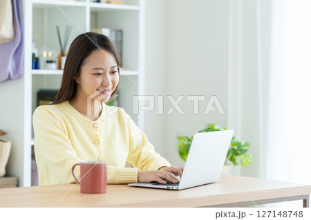 リビングでパソコンを使う若い女性 リビングでパソコンを使う若い女性 127148748