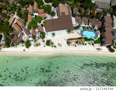 A beachside resort with a uniquely shaped pool surrounded by palm trees and overlooking turquoise waters. Rin Nai Beach. Ko Pha Ngan, Thailand. A beachside resort with a uniquely shaped pool surrounded by palm trees and overlooking turquoise waters. Rin Nai Beach. Ko Pha Ngan, Thailand. 127148749