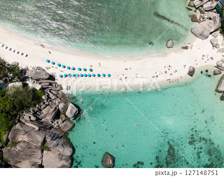 Sandy beach lined with umbrellas surrounded by clear turquoise waters and vibrant scenery. Thailand, Koh Tao. Sandy beach lined with umbrellas surrounded by clear turquoise waters and vibrant scenery. Thailand, Koh Tao. 127148751