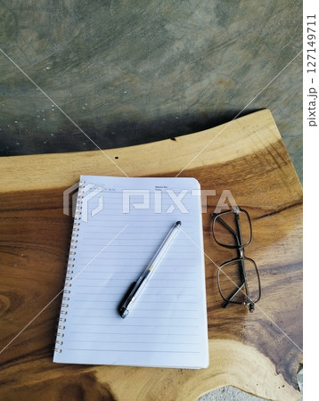 Open notepad with pen and glasses on wooden table. A Blank Sheet Of Notebook With The Items Of A Businessman. Ideal for branding and note-taking app presentations. Close up 127149711