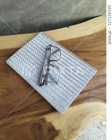 Notebook with pen and glasses on wooden table. professional workspace organization. Top view 127150185