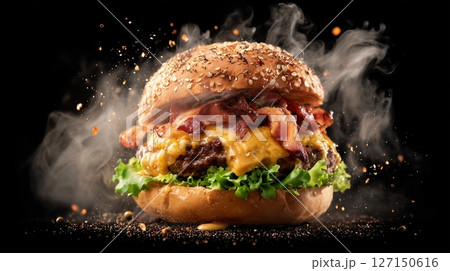 Juicy hamburger with melted cheese and crispy bacon surrounded by smoke and toppings for indulgent fast food craving Juicy hamburger with melted cheese and crispy bacon surrounded by smoke and toppings for indulgent fast food craving 127150616