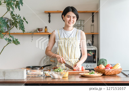 キッチンで料理をする若いアジア人女性（切る・包丁・クッキング・手料理） 127151037
