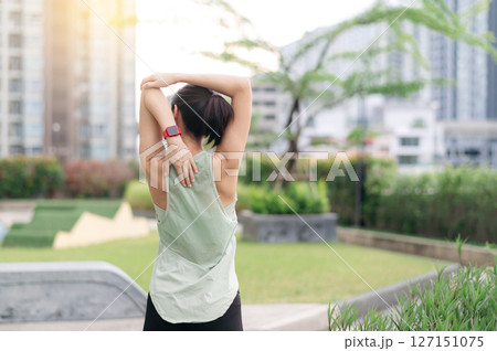 Asian woman fitness yoga workout. Stretching exercise reduces shoulder pain muscle strain medical injury risk inflammation. Urban city wellness and healthcare during peaceful sunset Asian woman fitness yoga workout. Stretching exercise reduces shoulder pain muscle strain medical injury risk inflammation. Urban city wellness and healthcare during peaceful sunset 127151075