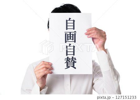 自画自賛と書かれた紙を持つ白いシャツを着た人物 自画自賛と書かれた紙を持つ白いシャツを着た人物 127151233