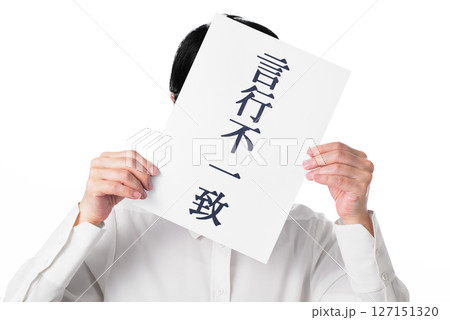 言行不一致と書かれた紙を持つ白いシャツを着た人物 127151320