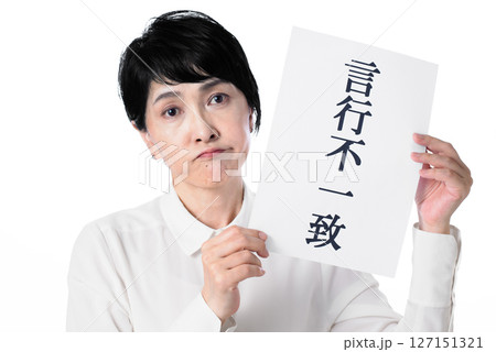 言行不一致と書かれた紙を持ち困っている中年女性 127151321