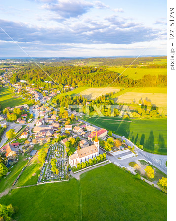 Bohutin Town showcases a picturesque landscape with lush fields and quaint homes. The historic church and cemetery are prominent features, illuminated by the warm glow of sunset. Bohutin Town showcases a picturesque landscape with lush fields and quaint homes. The historic church and cemetery are prominent features, illuminated by the warm glow of sunset. 127151759
