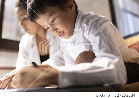 Young boy drawing next to his mother at home 127152234