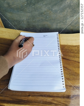 Hand Writing Notes in Journal on Light Wood Table Planning Concept Hand Writing Notes in Journal on Light Wood Table Planning Concept 127152357