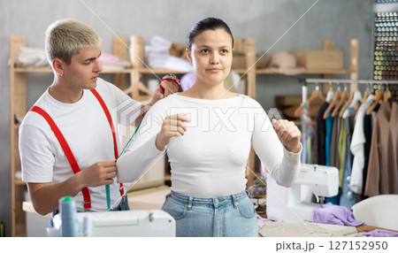 Male tailor taking measurements from Asian client 127152950