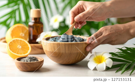 Gray body lotion in a wooden bowl with leaves as a backdrop. 127153131